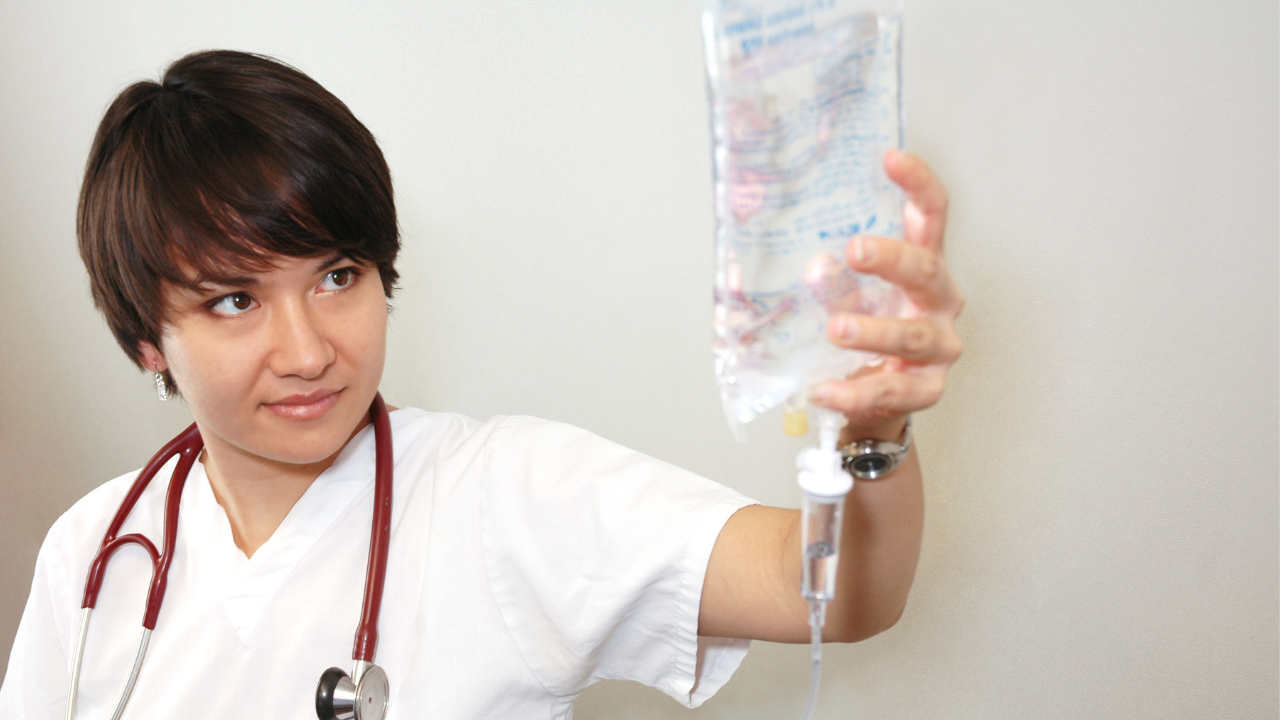nurse with stethoscope holding an intravenous saline infusion bag