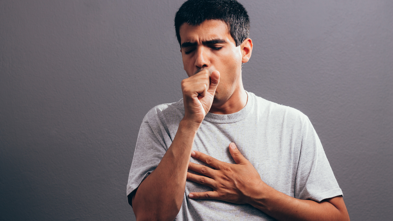 man coughing holding a clenched fist to mouth