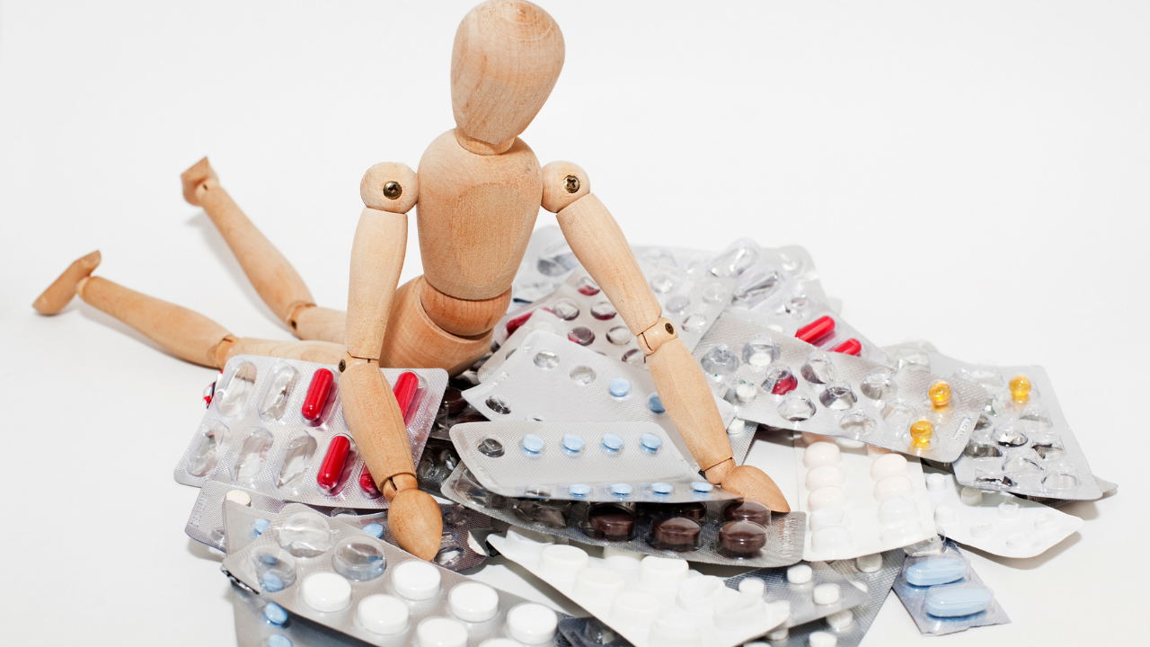 wooden doll falling on a pile of medications
