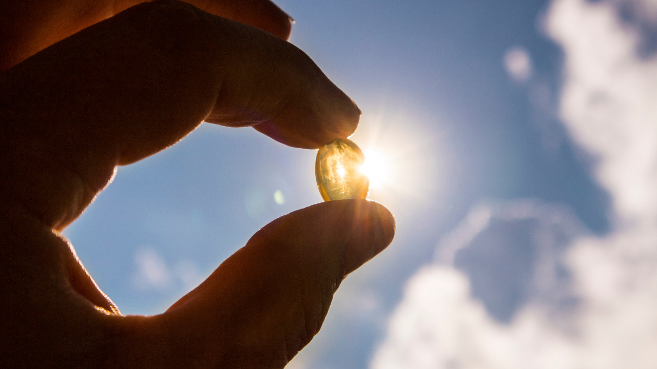 Fingers holding a Vitamin D capsule