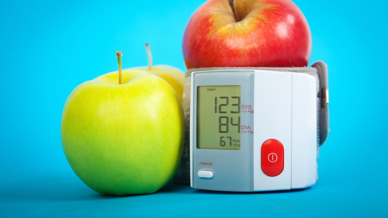 red and green apple next to a digital blood pressure monitor