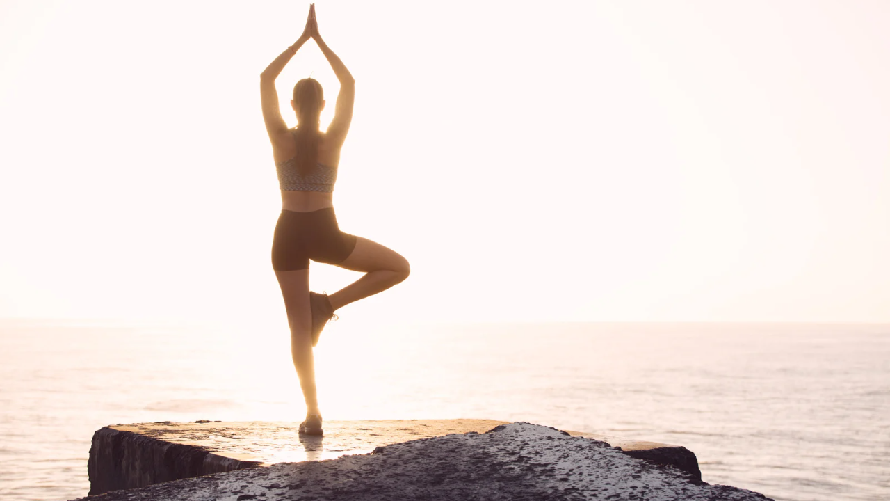 woman standing near the seashore in yoga pose