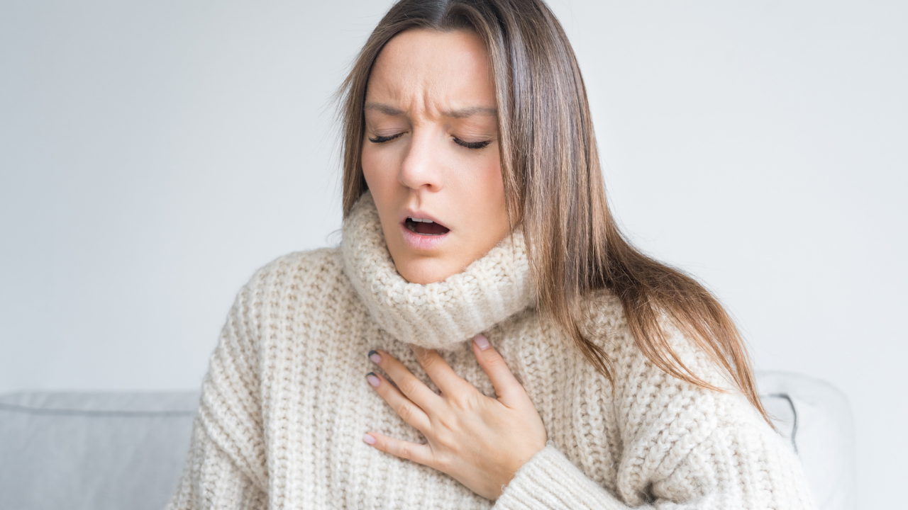 woman holding her chest while breathing hard