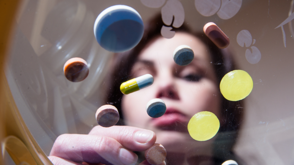 woman staring at multiple coloured pills