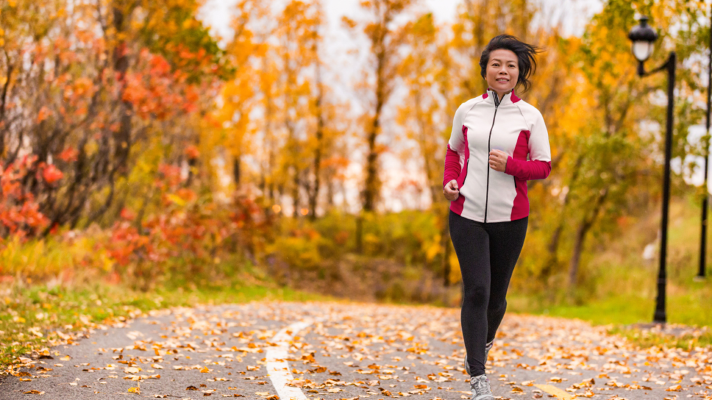 older woman running in a park during fall